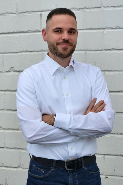 Yannik Kopp steht mit verschränkten Armen vor der Hauswand von GEDE GmbH